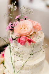 Weiße Hochzeitstorte mit rosa Blumen dekoriert