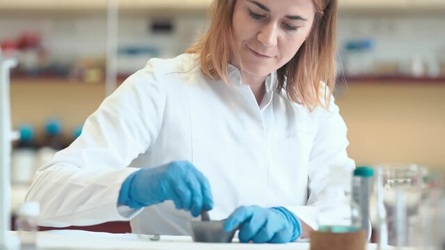crushing chemicals in a bowl with a mortar. a science university student will conduct research