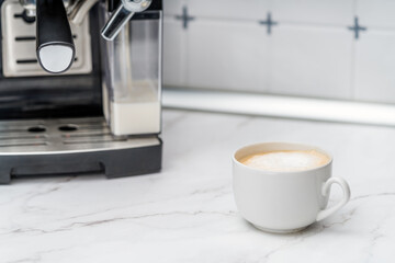 Cup with coffee latte in interior of kitchen. Domestic Household Appliances.