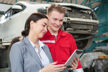 Female manager and car mechanic while working in auto repair shop, Woman at a car garage getting mechanical service, Car repair and maintenance concepts