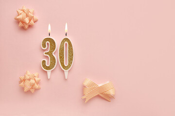 Number 30 on a pastel pink background with festive decorations. Happy birthday candles. The concept of celebrating a birthday, anniversary, important date, holiday. Copy space. banner