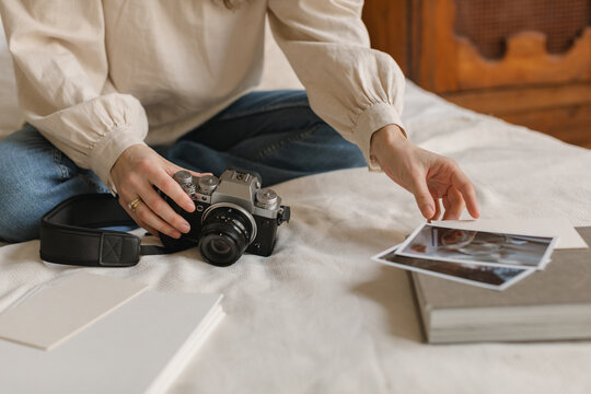 Close-up of a stylish woman sitting on bed with her camera looking at photos
