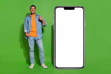 Fototapeta na wymiar Full length image of confident young male recommend phone application program isolated on green color background