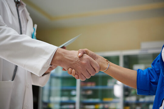 Closeup image of doctor shaking hand of patient when meeting her in hospital hall