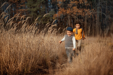 Two happy boys running together across the field with a cheerful scream and happiness on face. Portrait of happiness.