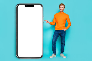 Photo of sweet attractive guy dressed orange sweater eyewear pointing modern device empty space isolated turquoise color background