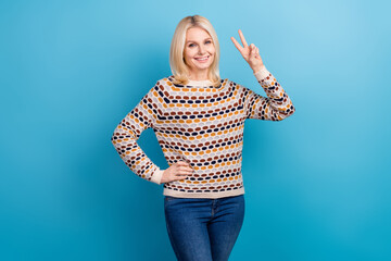 Fototapeta na wymiar Photo of excited charming lady dressed pullover showing v-sign smiling isolated blue color background