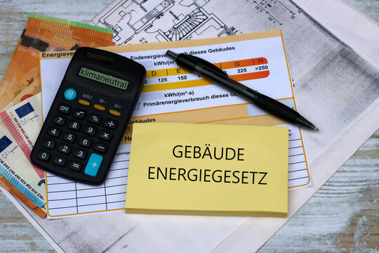 Kosten für Sanierung: Taschenrechner , Energieausweis, Geldscheine und der Text Gebäudeenergiegesetz auf einem Notizblock.
