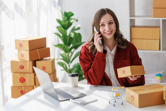 Concept of parcel delivery and selling online, Female seller or retailer using laptop to check sales of the day on online store to be packed into the parcel and ready to deliver to the customer