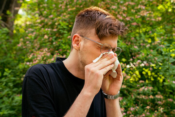 Young adult man having trouble with pollen seasonal allergies 