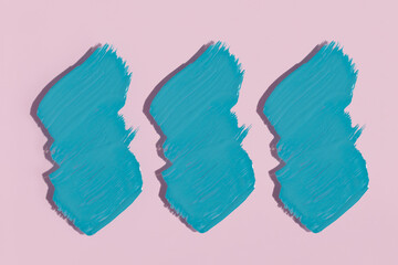 Three turquoise strokes isolated on a pink background. Paint stain watercolor texture, abstract hand painted.