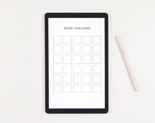  flat lay of digital tablet with template 30 day challenge on screen,  pink stylus pen,   isolated on white background.