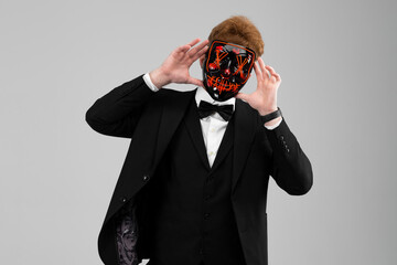Stylish young man in a sharp black formal suit wearing a bright face mask. Concealed identity and...