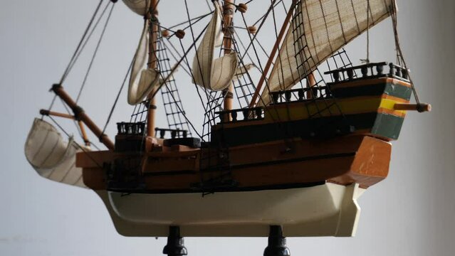 4K video of wooden model of three-masted sailing vessel on a stand rotates around closeup view