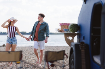 Young couple in front of van during summer vacation.