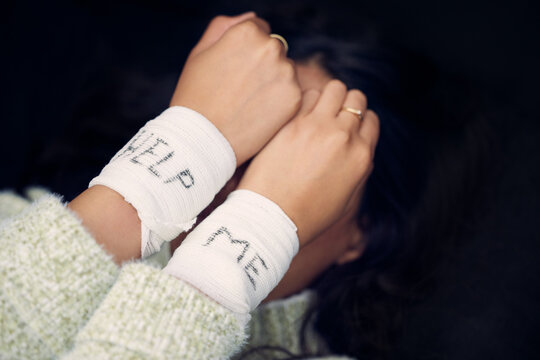 Hiding your hurt wont make it go away. a woman with bandages wrapped around her wrists showing help written on them.