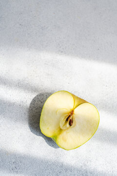 Overhead view of half an apple on a table in sunlight