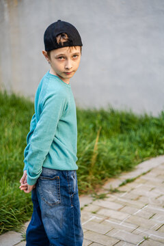 Portrait of a boy standing on a footpath with his hands clasped behind his back