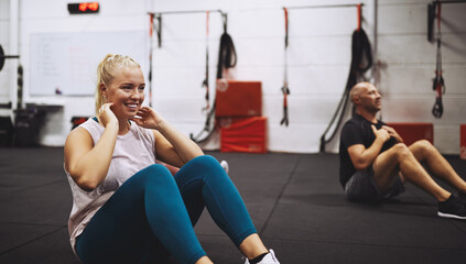 Smiling young woman doing sit-ups in a gym class