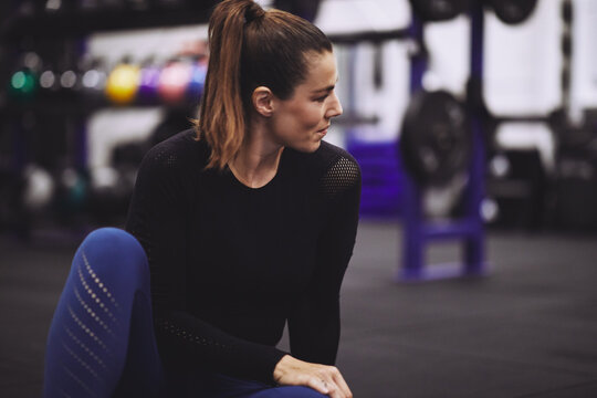 Young woman sitting on a gym floor after working out