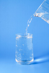 Pouring water into a glass on a blue background