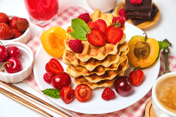 Healthy Breakfast set with Belgian waffles with strawberries, apricots, cherries, juice and a cup of black coffee and bitter chocolate on white stone table background
