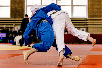 two judoka athletes fighting in red tatami, judo fight championship
