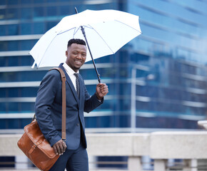 Im prepared for any weather. a young businessman holding an umbrella in the rain against a city...