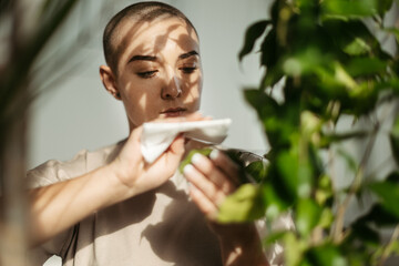 Young woman with cancer taking care of plants in her apartment.
