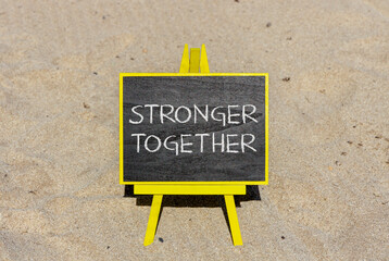 Stronger together symbol. Concept words Stronger together on black chalk blackboard on a beautiful sand beach background. Business, motivational and stronger together concept.