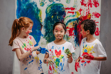 Portrait of happy kids with finger colours and painted t-shirts, studio shoot.