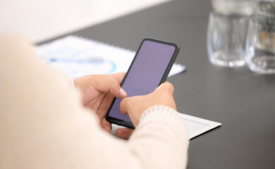 Checking on some business updates. Closeup shot of an unrecognisable businessman using a cellphone with a blank screen in an office.