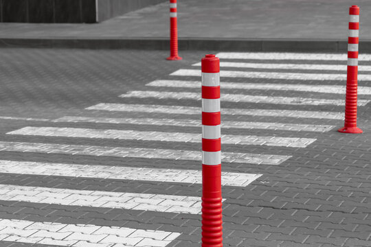 Empty pedestrian crossing and rubber signal posts. Red rubber column. Empty zebra. Lines on the road. Safety on the road. Signs for pedestrians. Rubber signal posts. Road markings.