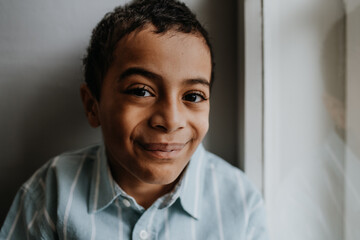 Portrait of multiracial boy sitting near the window.