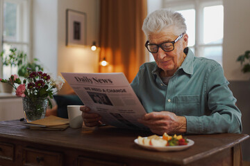 Senior man reading newspaper in his apartment.