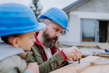 Father and his little son working in front of their unfinished house.