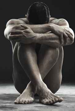 The strong can also be vulnerable. Monochrome shot of a muscular young man posing nude in studio against a dark background.