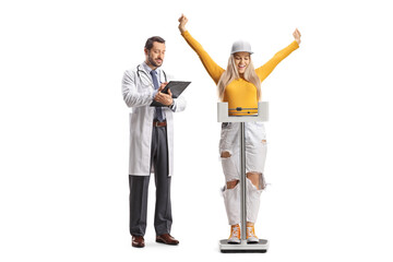 Doctor writing a document and young female student standing on a weight scale and gesturing happiness