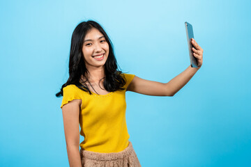 Portrait, asian girl long hair wearing fitted shirt, stand holding laptop raised high above head in distance that selfie camera in front beautiful angle, Isolated indoor studio on blue background.