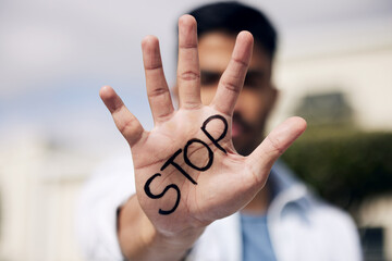 Stop waiting for change and make it yourself. a young man showing his hand with the word stop written on it outside at college.