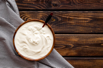 Sour cream or yogurt in wooden bowl. Dairy product background