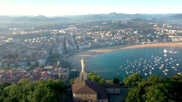 Sensational 4k footage of San Sebastian - Donostia city at sunrise. Beautiful warm colours. View of the Jesus Christ Statue, guarding and protecting the city. In background, the old tow center. 