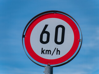 A road sign limiting the speed to 60 km h on a blue sky background.