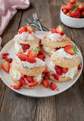 Strawberry dessert with traditional english shortcakes with vanilla whipped cream and marinated strawberries on wooden table