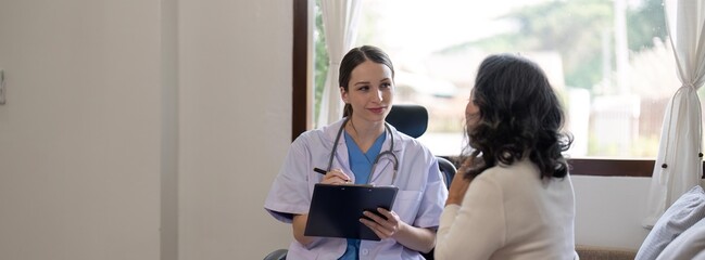 Female doctor is examining elderly patient while taking notes of illness. Health care concept