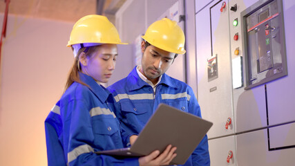 Professional electrical engineer team using laptop computer to inspecting the electrical circuit in control room.