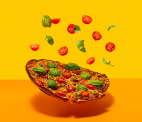 Pizza Margherita with basil tomato and mozzarella levitating over a wooden surface.