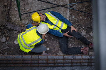 A young Asian builder falls from a scaffold at a construction site. An engineer supervising the construction came to the aid of a construction worker who fell from a height with hip and leg injuries.