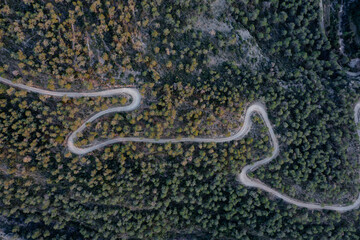 Aerial shot of a curvy road on a mountain in a forest
