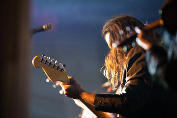 Band playing music and a gig in a venue, close up of a rock band playing guitars and instruments.